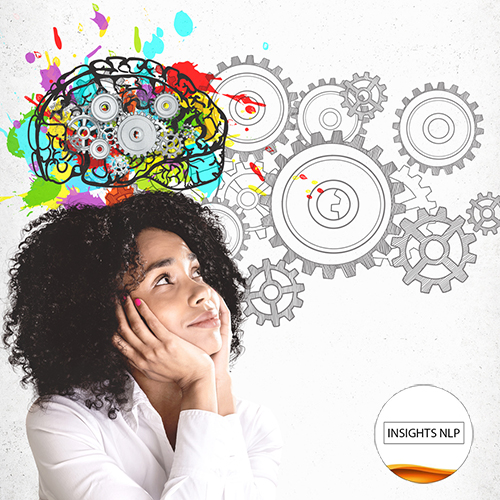 Smiling young African American woman in white shirt looking at colorful brain sketch with gears drawn on concrete wall. Concept of brainstorming